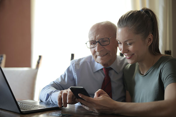senior man and young woman watching smartphone