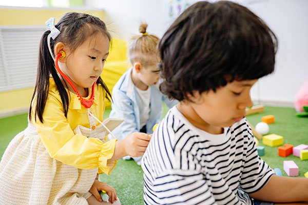 Three kids playing with a stethoscope in a classroom