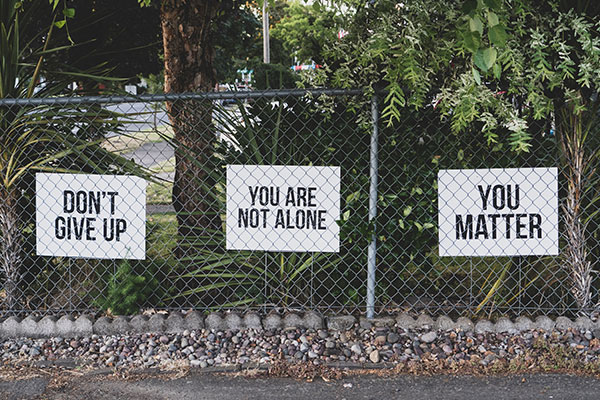 mental health signs on a chain link fence