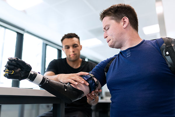 young man wearing a blue shirt gets fitted for a prosthetic arm
