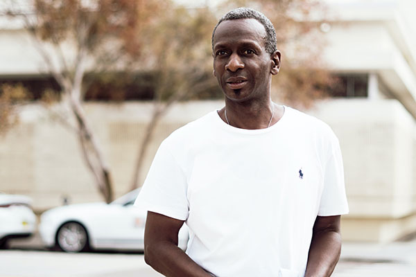 black man in white shirt walking down the street
